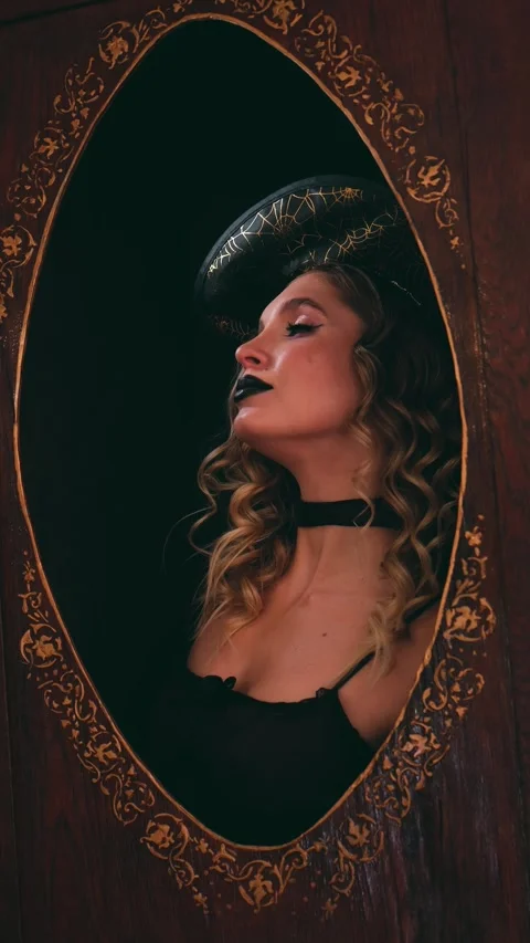 Glamorous young witch with black lipstick and dramatic makeup looking at her Stock Footage 342068253