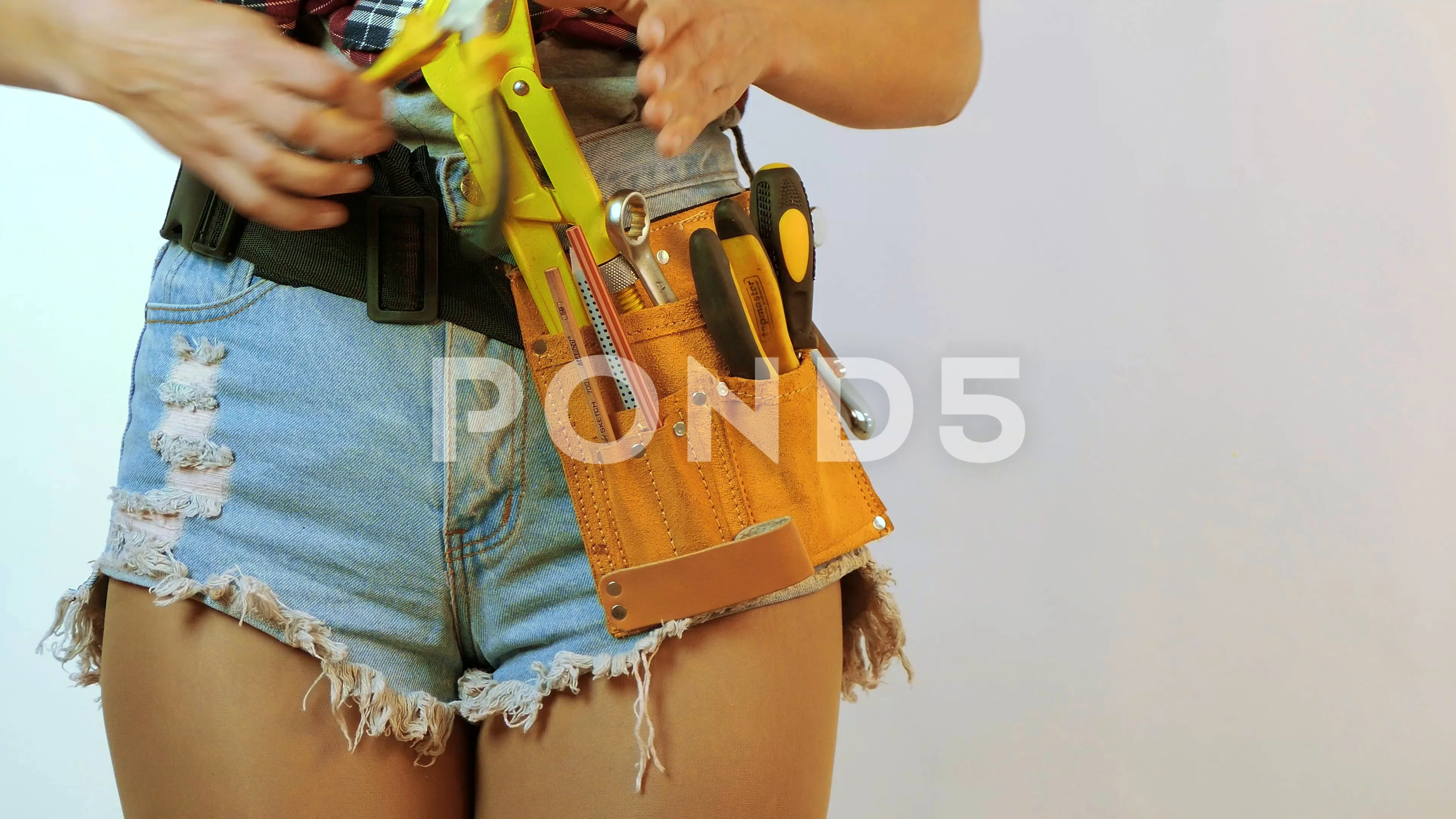 Glamour model in Daisy duke shorts and tool belt with work tool