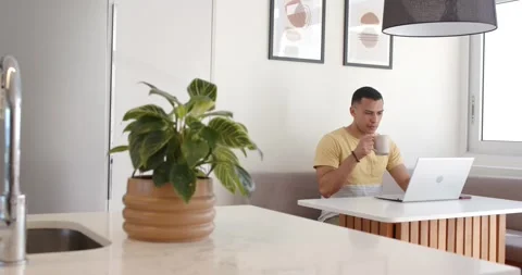 Glancing at laptop screen, man lifting mug and sipping coffee during work Stock Footage 334924009