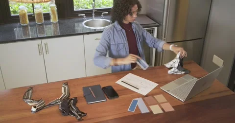 Glancing swatches, non binary person sketching at island beside laptop, typing, Stock Footage 337704707