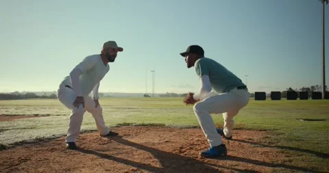 Glancing at watch, coach and player squatting on sunlit baseball mound Stock Footage 340392241