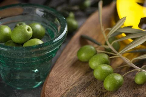 Glas cup of olives with extra virgin olive oil in glass bottle on rustic back Stock Photos