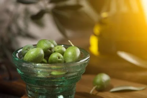 Glas cup of olives with extra virgin olive oil in glass bottle on rustic back Stock Photos