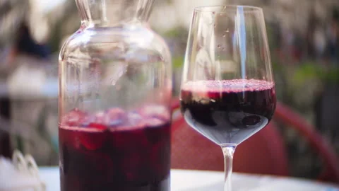 A glass and a pitcher of cold red sangria with ice cubes. Stock Footage 337139786
