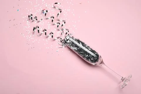 Glass and shiny confetti on pink background, above view Stock Photos