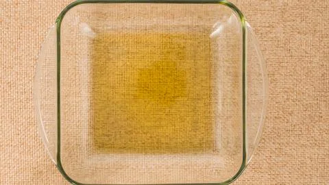 A glass baking dish with layer of olive oil close-up on a kitchen table, fl.. Stock Photos