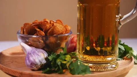 Glass of beer on a plate with bread crackers, bacon, cherry tomatoes and greens Stock Footage 124376559