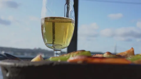 Glass of beer rests on a table alongside a plate of food Stock Footage 292398039