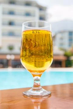 Glass of beer on the table on the background of the pool and the hotel Stock Photos