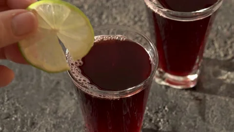 A glass of black elder syrup is being decorated with lime Video stock 169052028