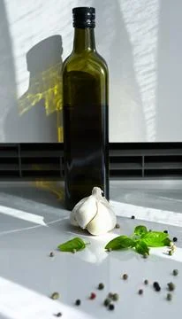 Glass bottle of extra virgin olive oil with fresh garlic, basil leaves, and pepp Stock Photos