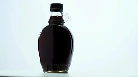 Glass bottle of maple syrup rotating on white background Stock Footage 333810899