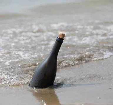 Glass bottle with a message inside transported from the sea to the shore Stock Photos