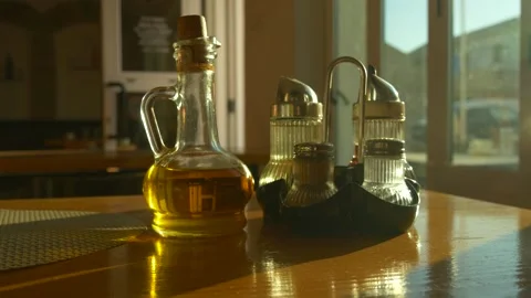 Glass bottle of olive oil on table in warm restaurant light Stock Footage 330535779