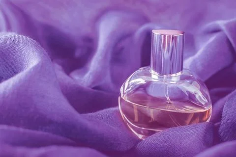 Glass bottle with perfume on background of very peri purple fabric. Macro close 스톡 사진