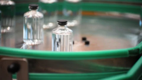 Glass bottles move on in a sorting circle. Pharmaceutical equipment. Stock Footage 99225007