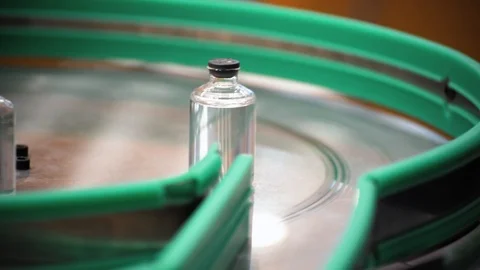 Glass bottles move on in a sorting circle. Pharmaceutical equipment. Stock Footage 99919078