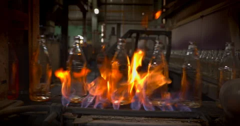 Glass bottles pass through flames in the annealing process at a glass factory Stock Footage 303107140