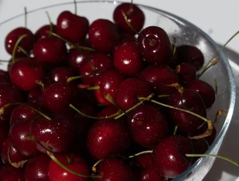 Glass bowl of fresh sweet cherry on a white background Stock Photos