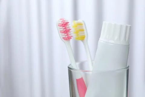 Glass with brushes and toothpaste on blurred background. Space for text Stock Photos