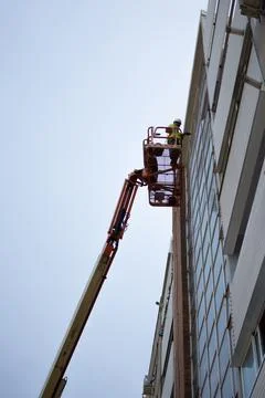 Glass Canvas Symphony: Worker Elevating Craft on Skyscraper Stock Photos