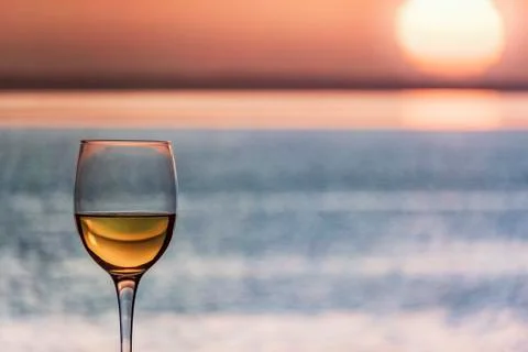 Glass of Chardonnay White Wine Overlooking the sea during the sunset Stock Photos
