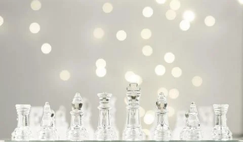 Glass chess on a light background with blurred lights and highlights. Фото