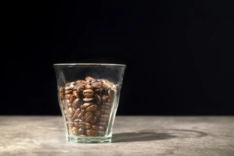 Glass with coffee beans on the table Stock Photos