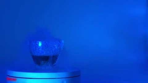 Glass coffee mug with bubbling liquid on white platform neon lighting Stock Footage 311397366