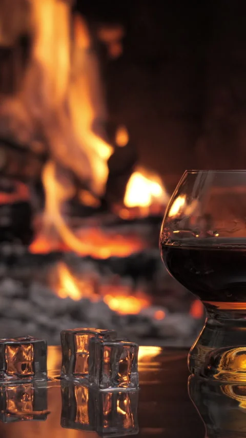 Glass with cognac on the background of fire in the fireplace Stock Footage 335124851