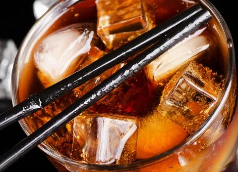 Glass of cola with ice cube. Selective focus Stock Photos