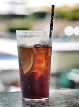 Glass of cola with ice cube, slice of lemon and straw in glass. Stock Photos