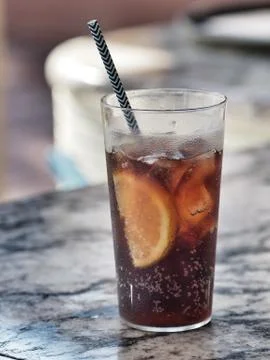 Glass of cola with ice cube, slice of lemon and straw in glass. Foto stock