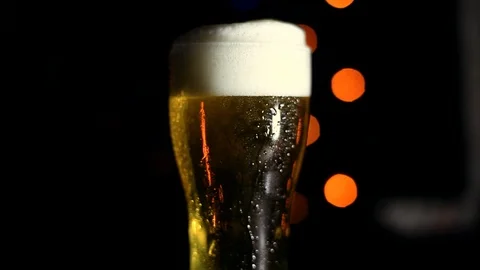 A glass of cold beer on a black background with colored lights. Drops of water Stock Footage 89960714