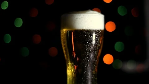 A glass of cold beer on a black background with colored lights. Drops of water Stock Footage 89960798