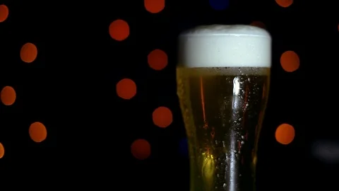 A glass of cold beer on a black background with colored lights is on the bar Stock Footage 89961213
