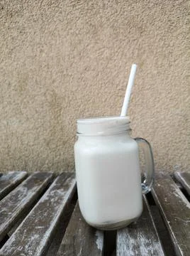 Glass of cold coffee on a background of a wall on a wooden table, front view Stock Photos