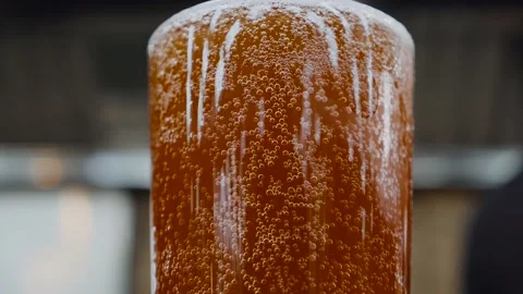 Glass of cold dark beer on a colored background. Bubbles slowly rise up. Craft Stock Footage 131492806