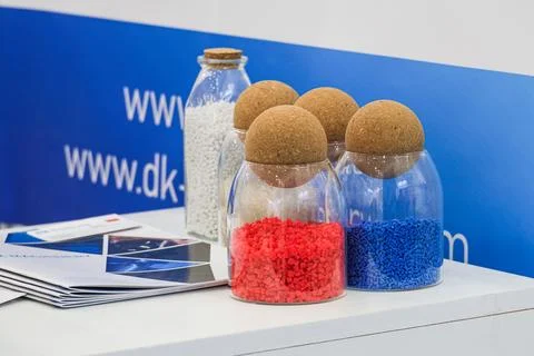 Glass containers with colored plastic granules for cable insulation production. Stock Photos