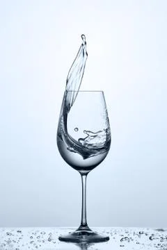 Glass of cool cleaner splashing water while standing on the glass with water Stock Photos