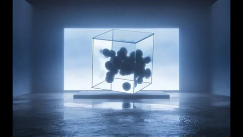 Glass cube full of dark spheres tumbling before a glowing wall screen Stock Footage 346780916