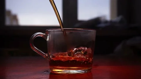 A glass cup is being filled standing on a wooden table with a widow on backgroun 스톡 동영상 168248391