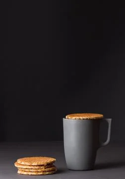 A glass cup of black tea with stack of dutch waffles on dark grey background. Stock Photos