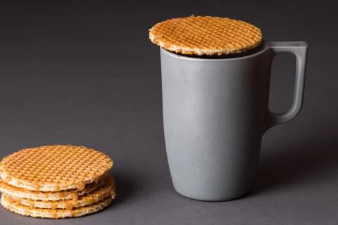 A glass cup of black tea with stack of dutch waffles on dark grey background. Stock Photos