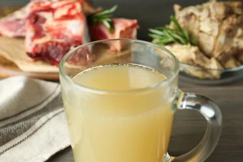 Glass cup with delicious bone broth on table, closeup Stock Photos
