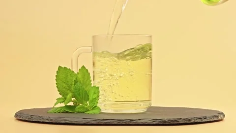 Glass cup filled with fresh mint herbal tea on a stone tray. Stress relief drink Stock Footage 318882169