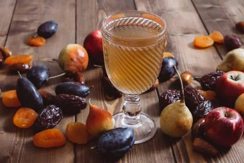 A glass cup with fruit compote and ripe apricots on a wooden table. Stock Photos