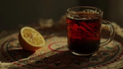 Glass cup of hot black tea with lemon slice on embroidered napkin, cozy autu Vidéo 346252170
