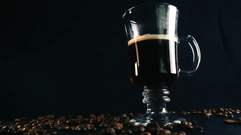 Glass cup of hot coffee with beans rotating on black background Stock Footage 341324103