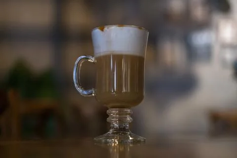 Glass cup with latte is on the table in coffee shop. Stock Photos